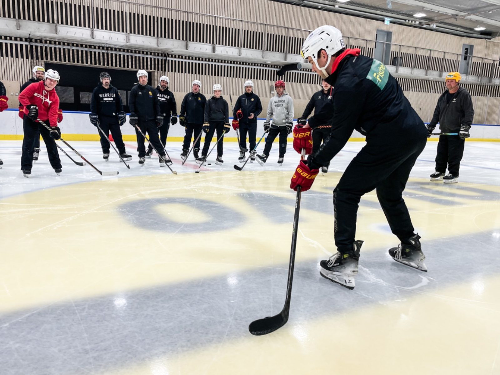 Trainer erklärt einer Gruppe eine Übung auf dem Eis